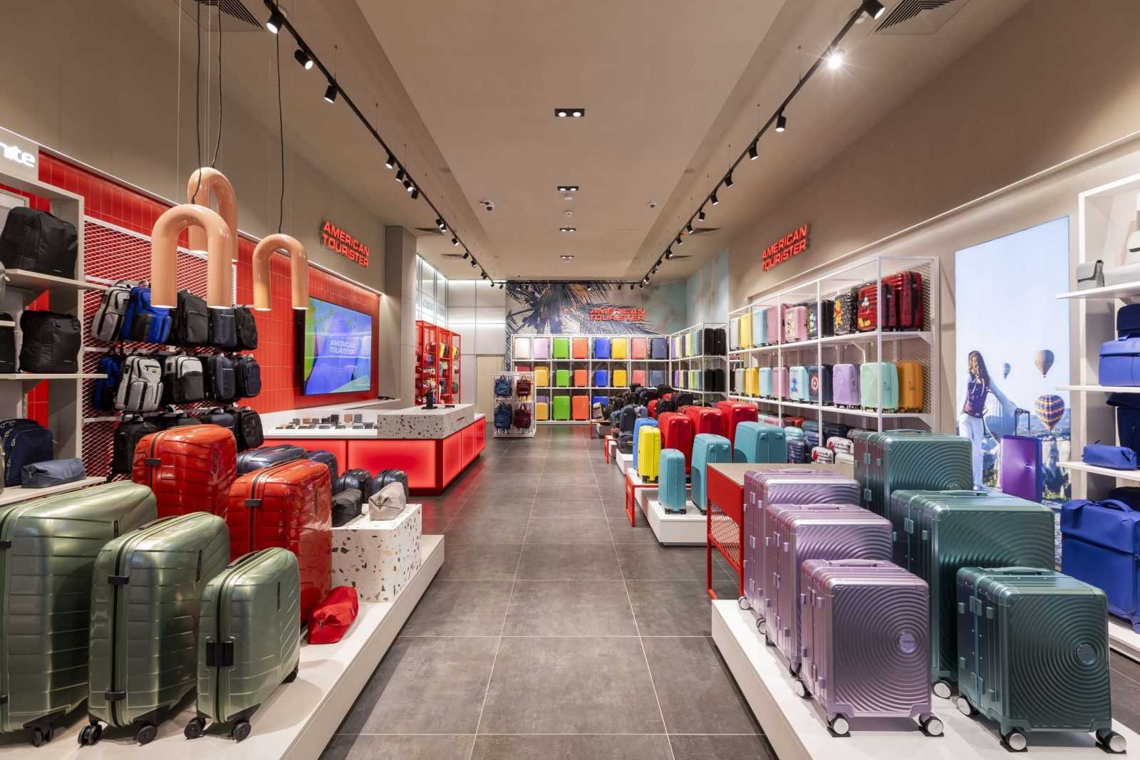 American Tourister store interior with colorful suitcases and backpacks.