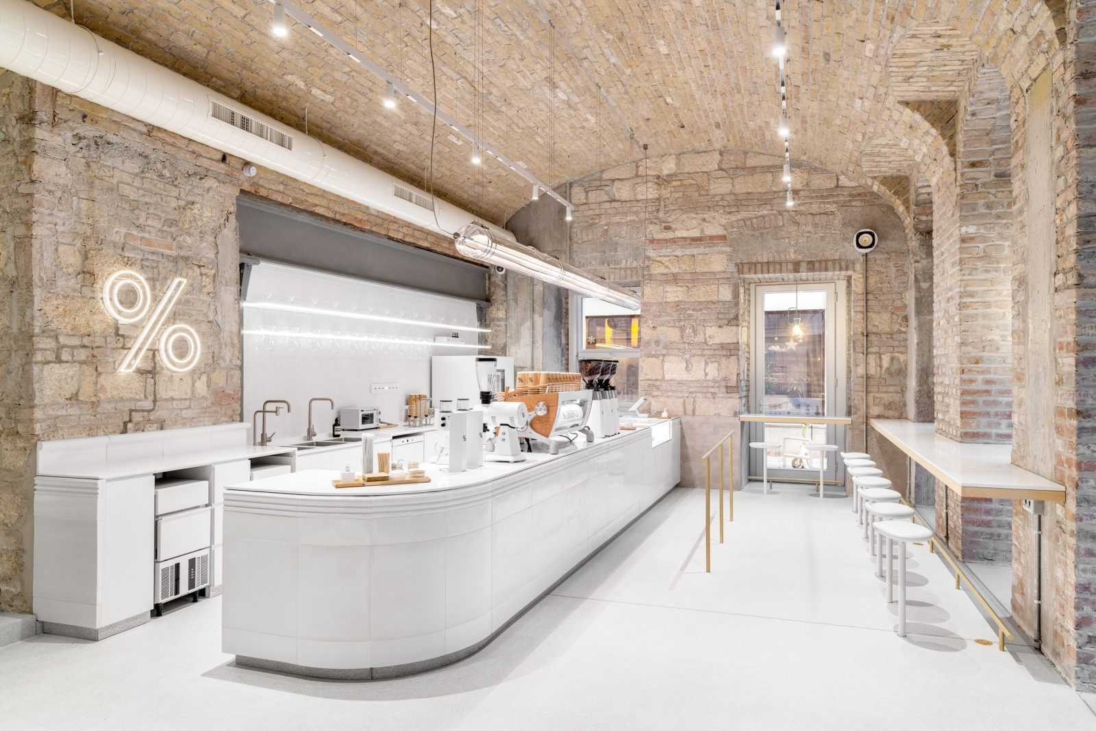 Modern coffee shop interior with exposed brick walls and white counter.