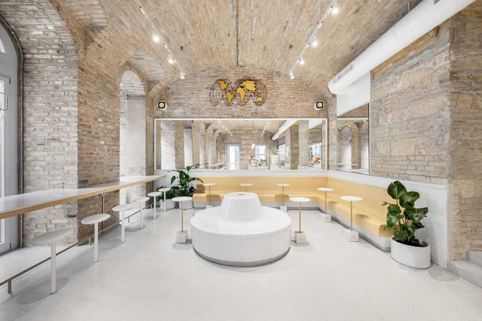 Modern café interior with exposed brick walls and white seating.