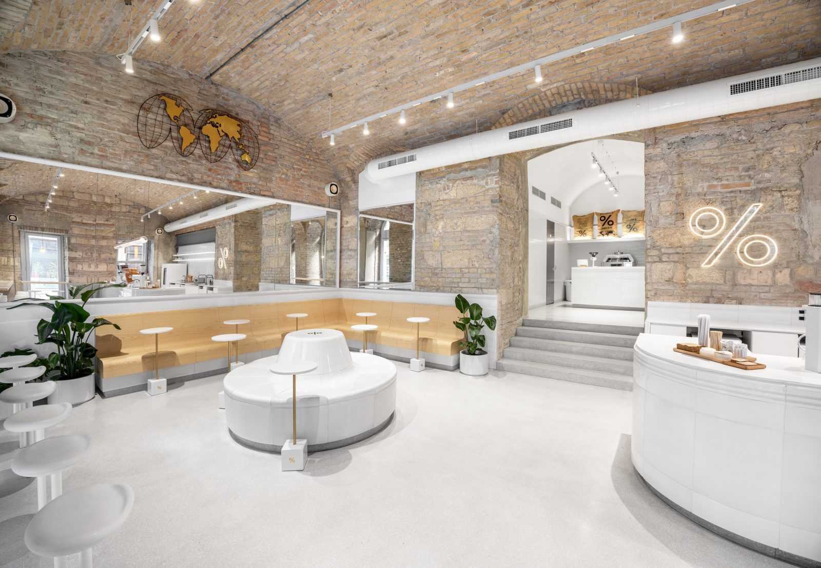 Modern coffee shop interior with exposed brick walls and neon % sign.