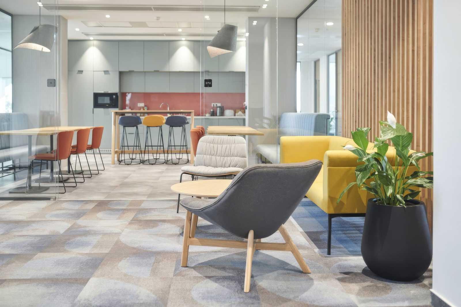 Modern office lounge with colorful chairs and wooden accents.