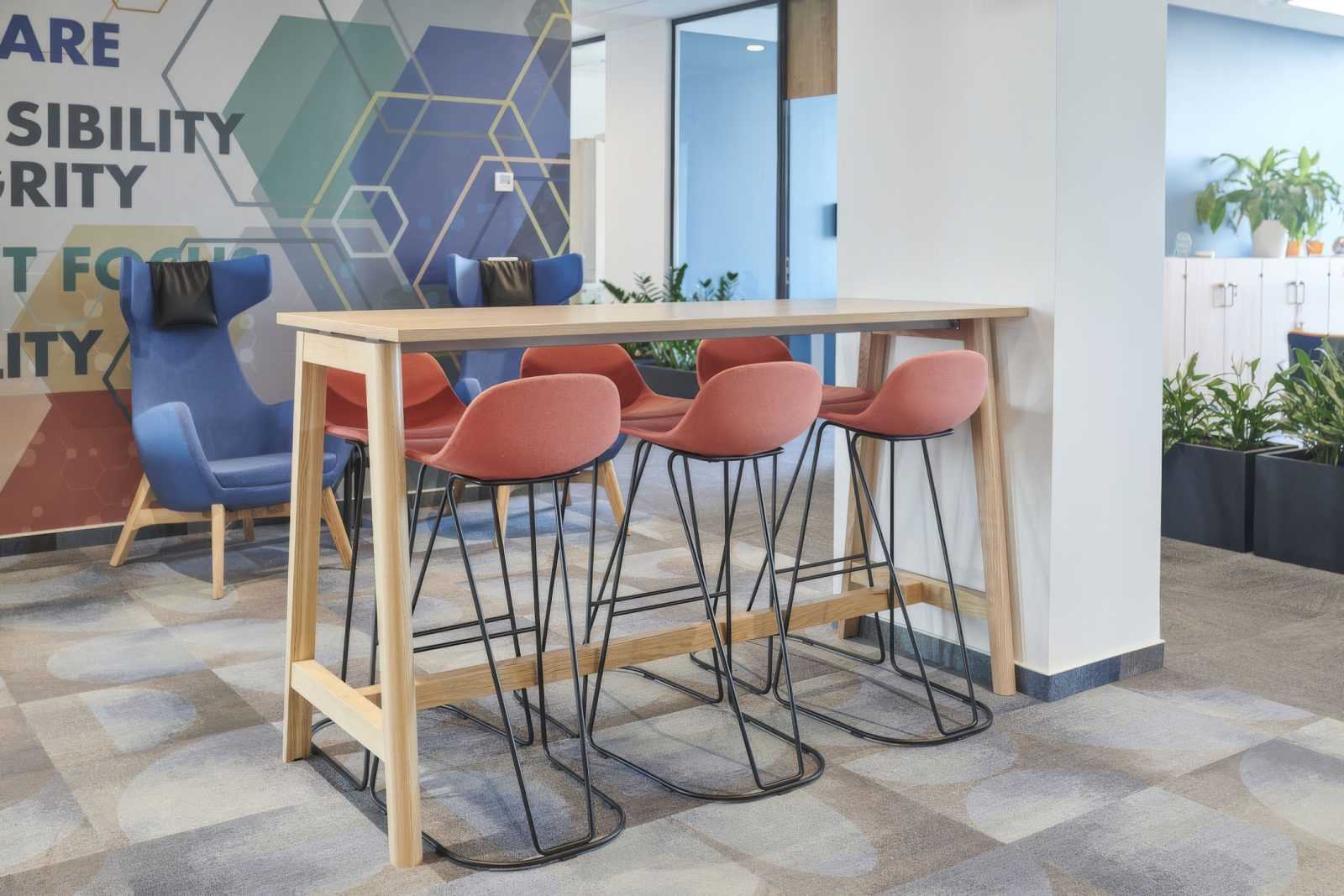 Modern office seating with wooden table and colorful bar stools.