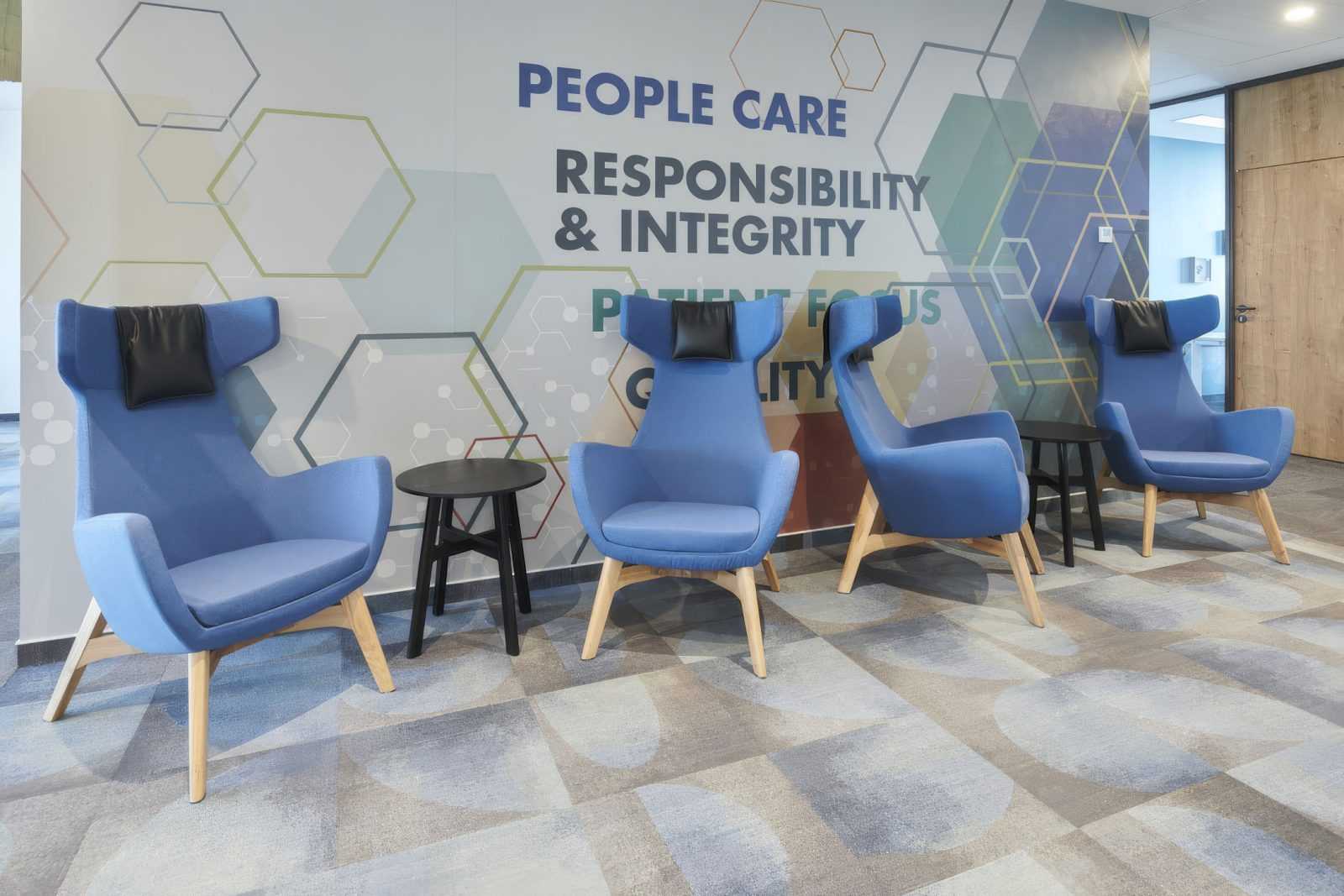 Modern blue chairs in a waiting area with 'People Care' wall mural.
