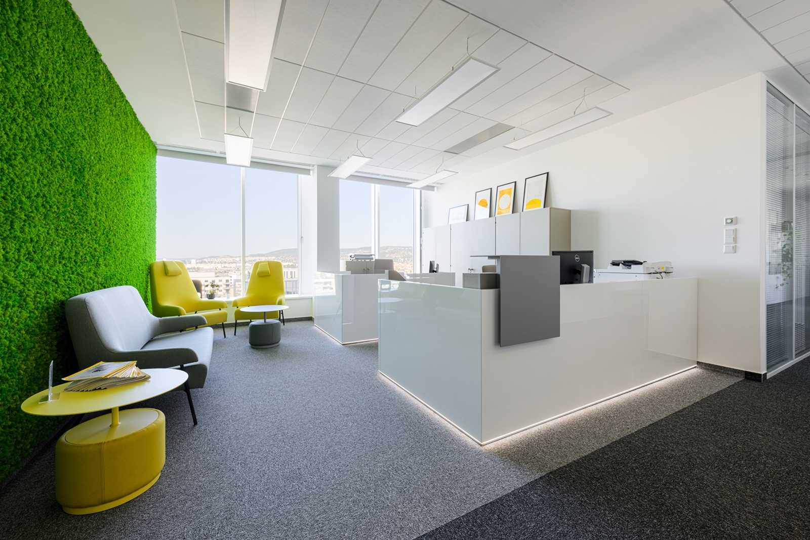 Modern office reception with green wall and yellow chairs.