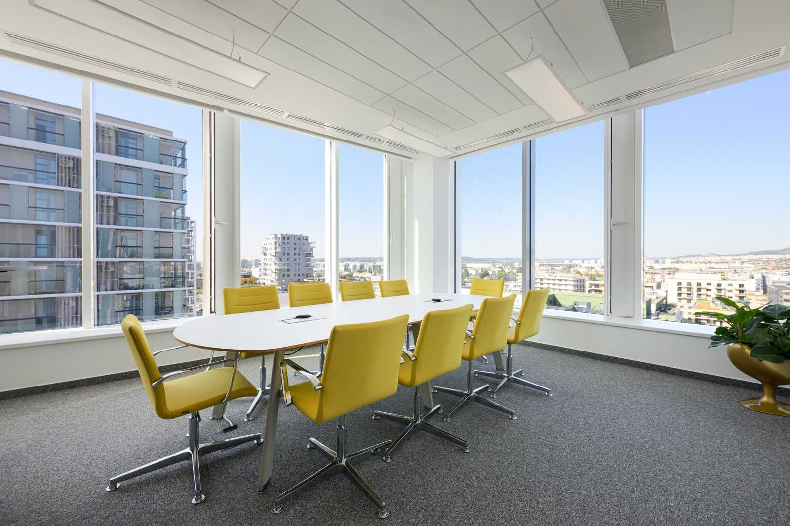 Modern conference room with yellow chairs and city view.