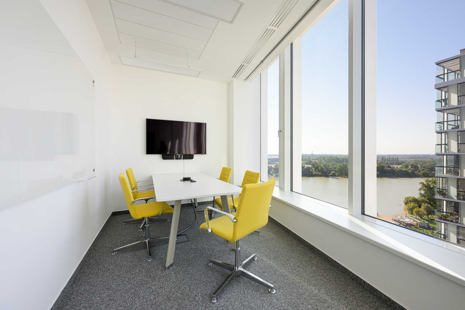Modern conference room with yellow chairs and river view.