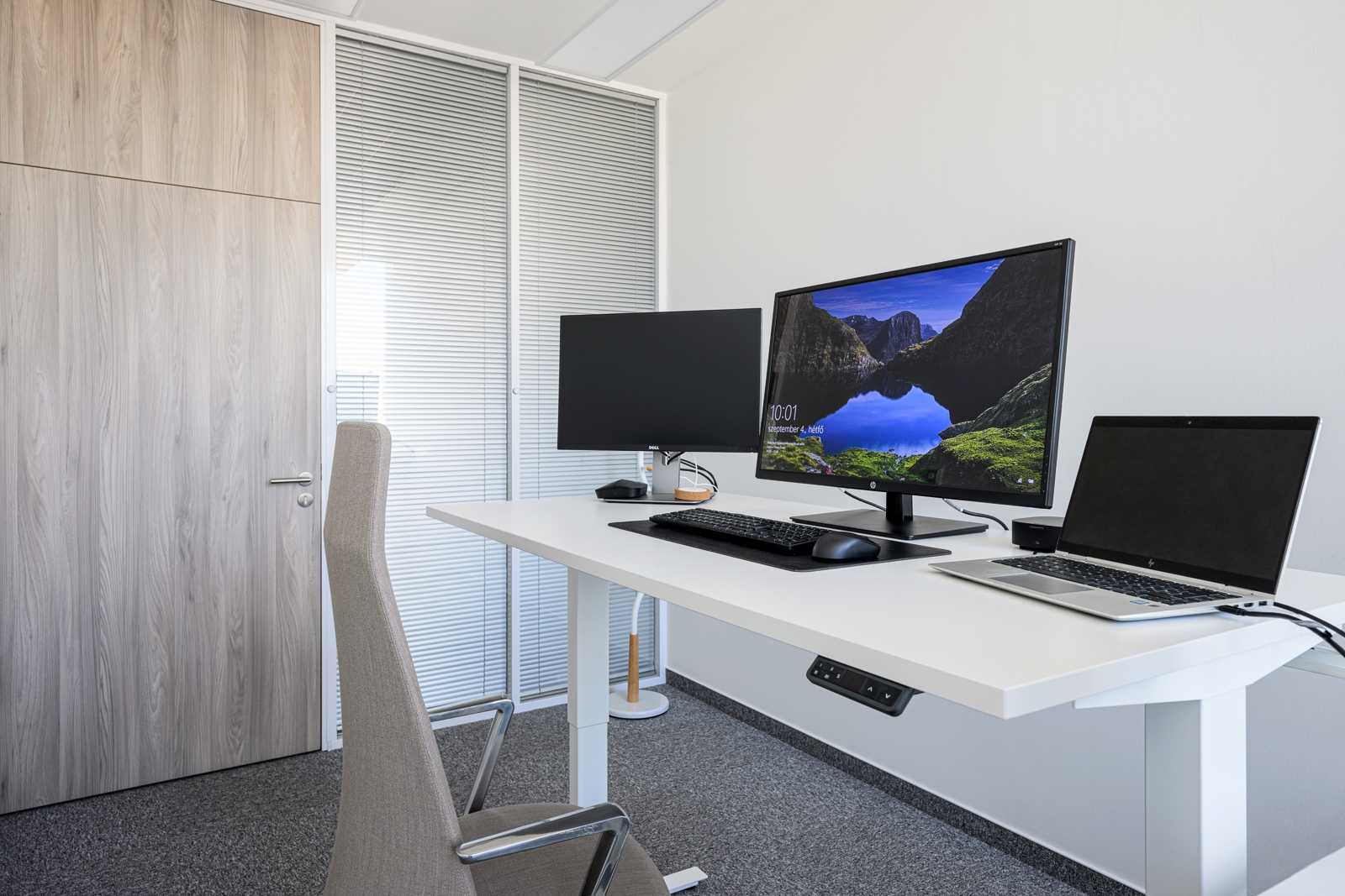 Modern office desk with dual monitors and laptop.
