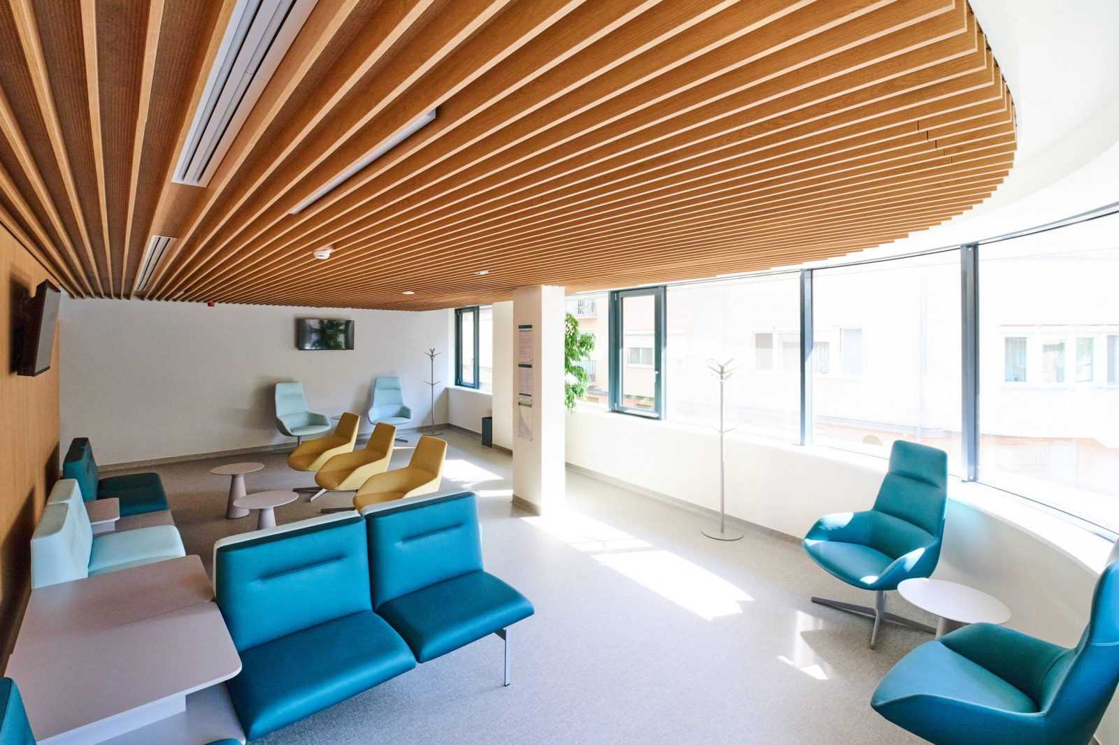 Modern waiting room with wooden ceiling and colorful chairs.