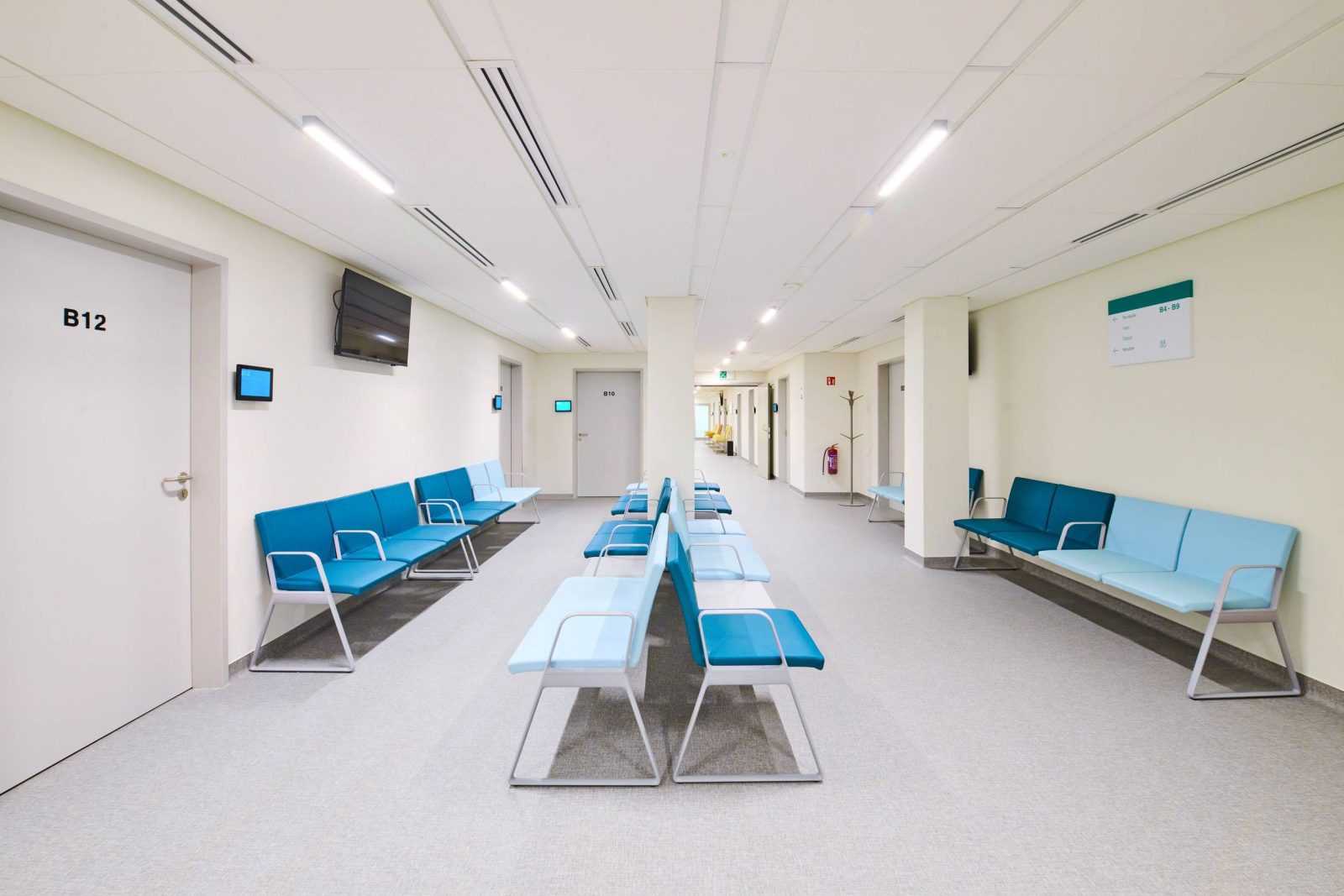 Modern hospital waiting room with blue chairs and clean design.