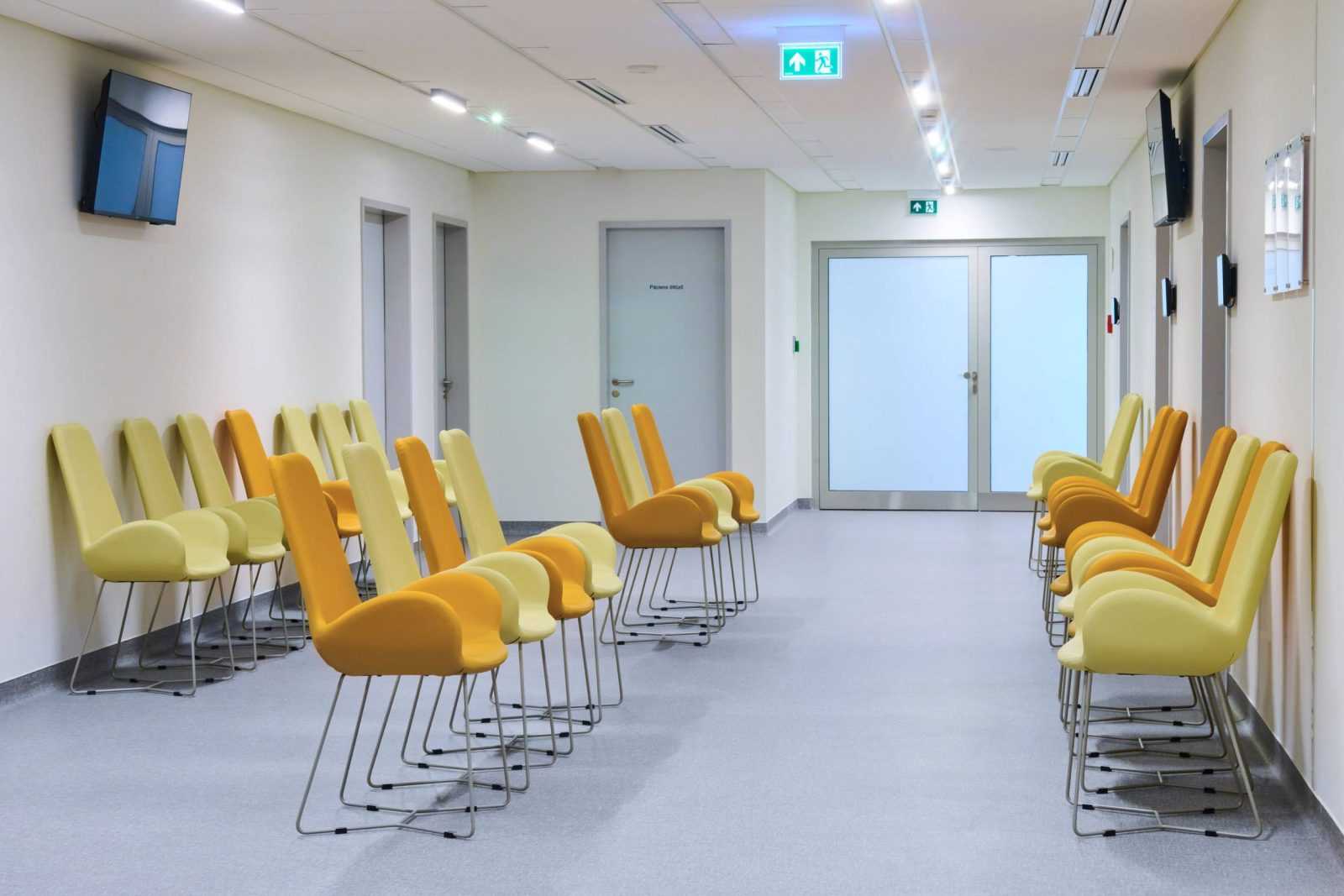 Modern hospital waiting room with yellow chairs and clean design.