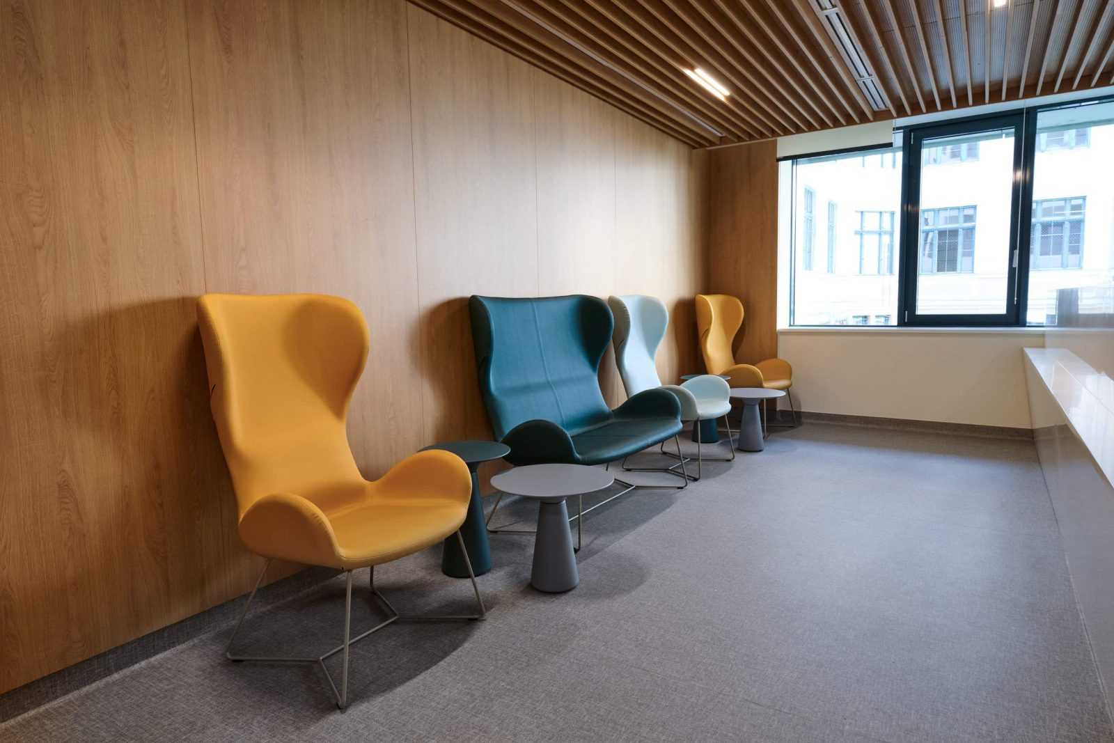 Modern colorful chairs in a wooden office lounge.