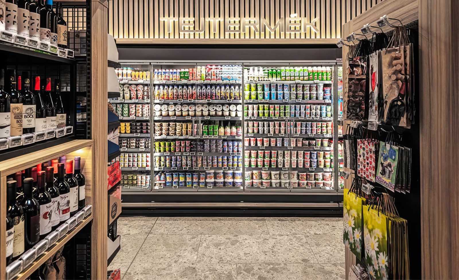 Dairy section at Megaholz store with refrigerated shelves and wine bottles.