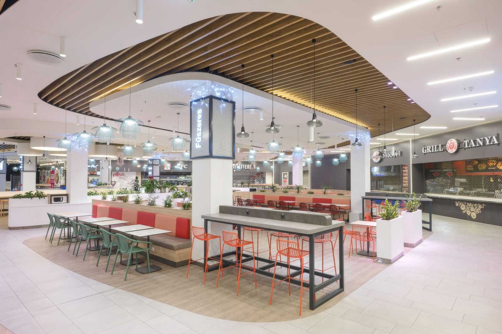 Modern food court with colorful seating and wooden ceiling at Megaholz.