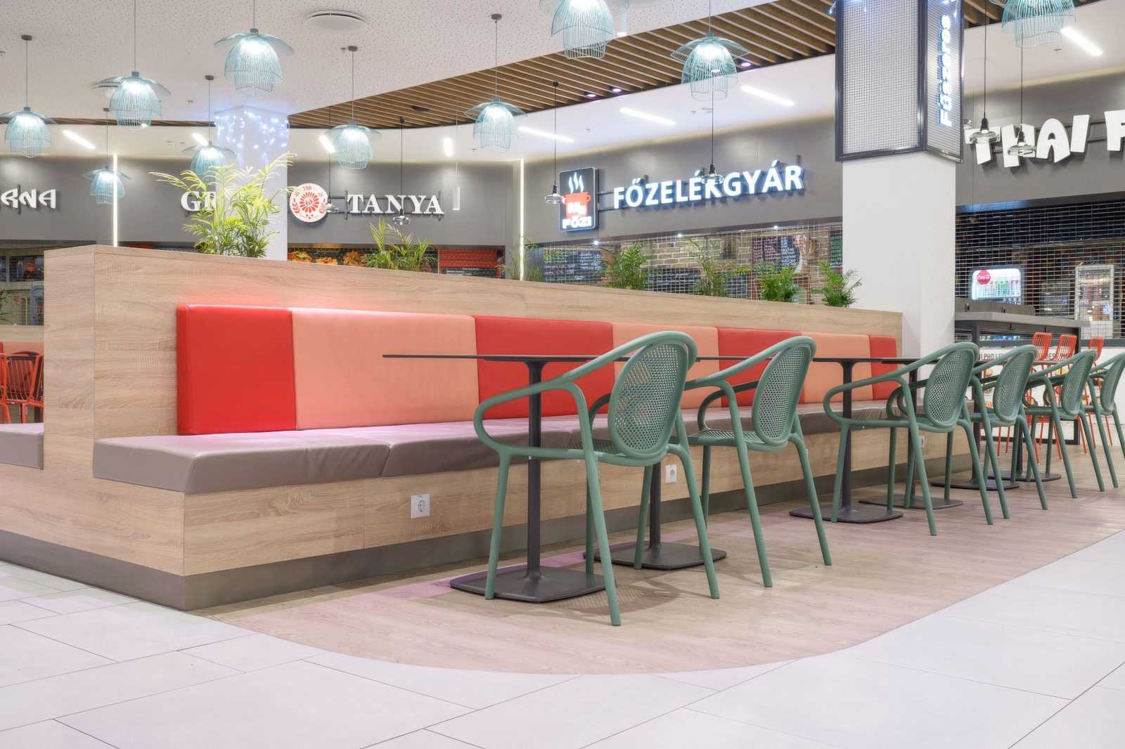 Modern food court seating with colorful booths and hanging lights.