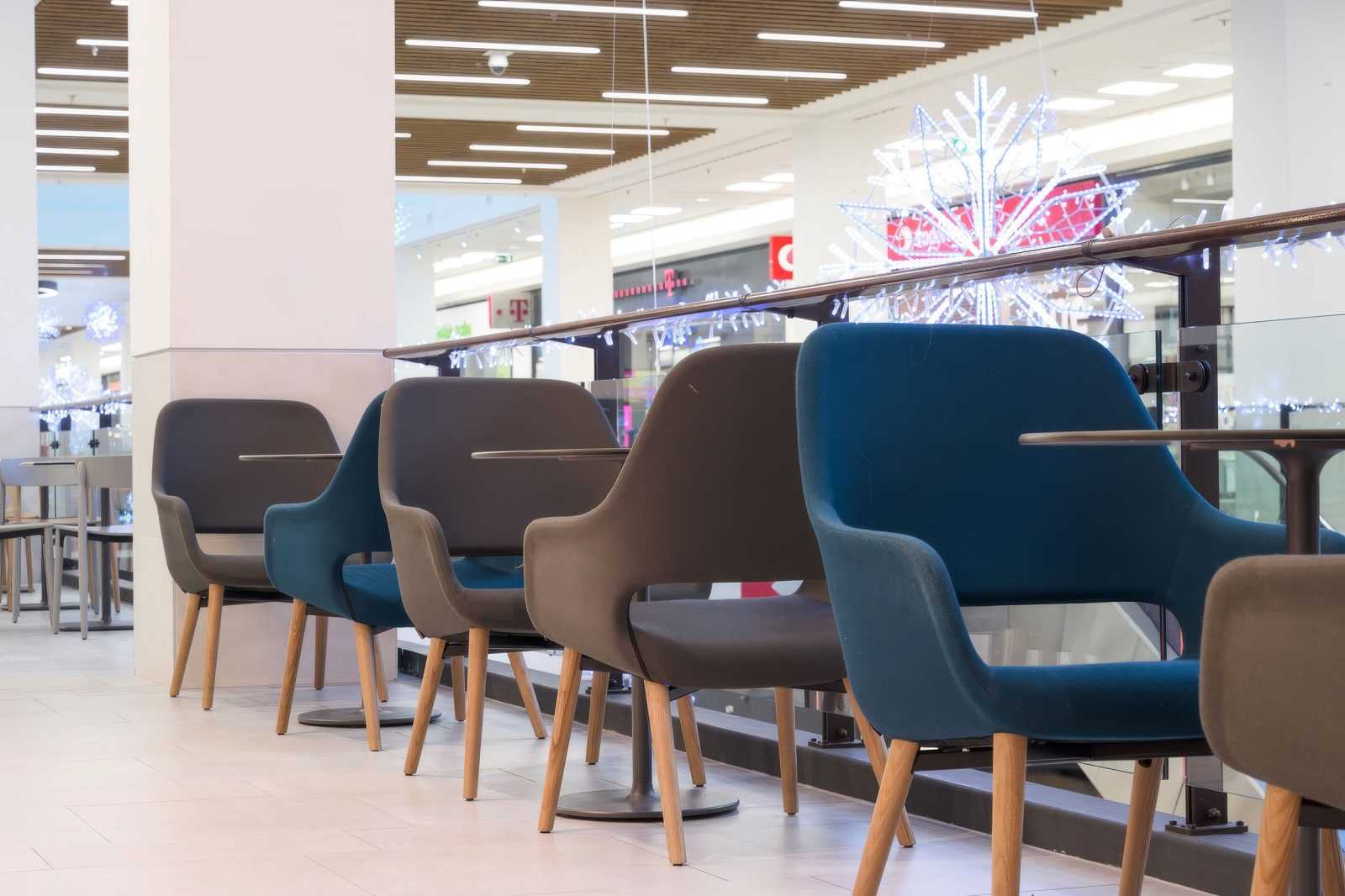 Modern chairs in a shopping mall with festive lights.