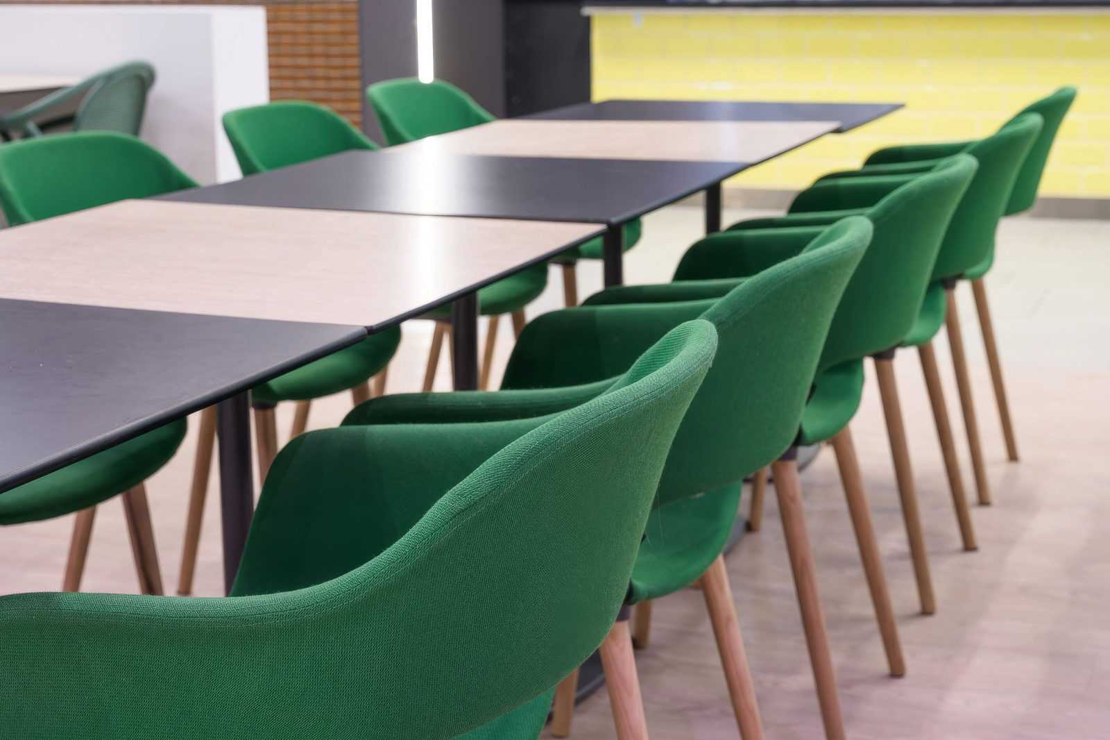 Modern green chairs and tables in a stylish office or cafe setting.