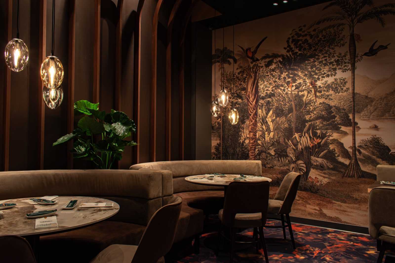 Luxury restaurant interior with jungle mural and modern lighting.