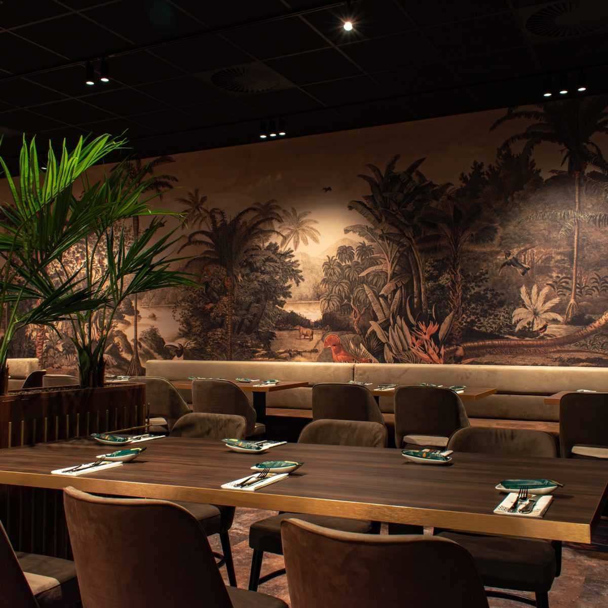 Luxury restaurant interior with jungle mural and tropical plants.