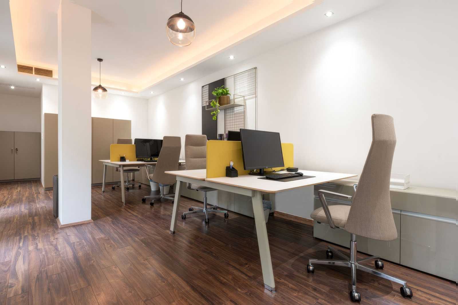 Modern office workspace with ergonomic chairs and wooden flooring.