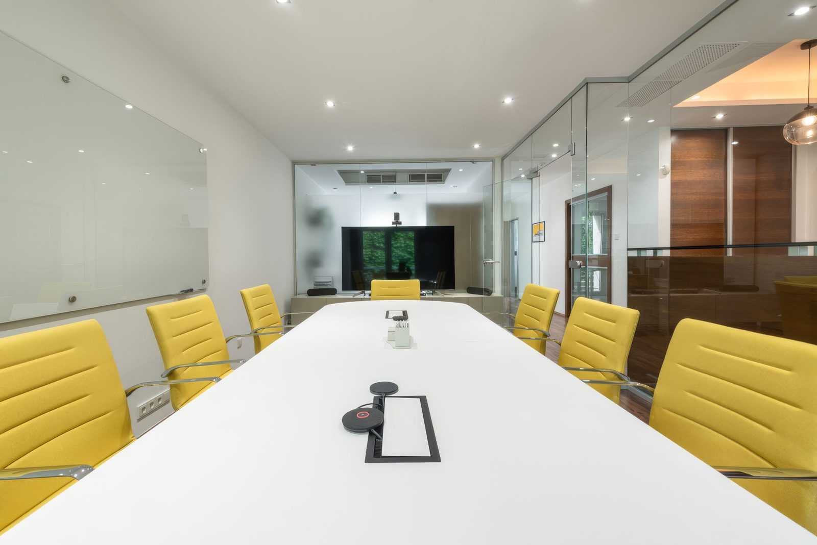 Modern conference room with yellow chairs and glass walls.