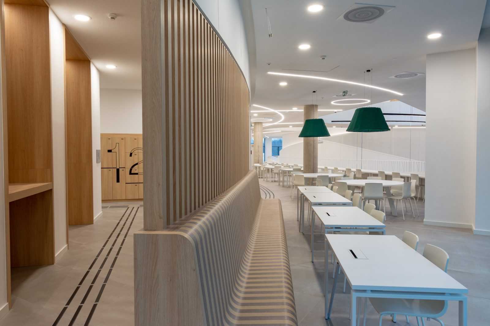 Modern wooden interior with curved bench and white tables.
