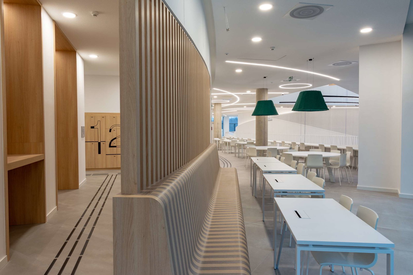 Modern wooden interior with curved bench and white tables.