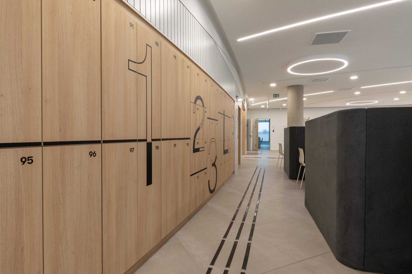 Modern wooden lockers with large numbers in a sleek office hallway.