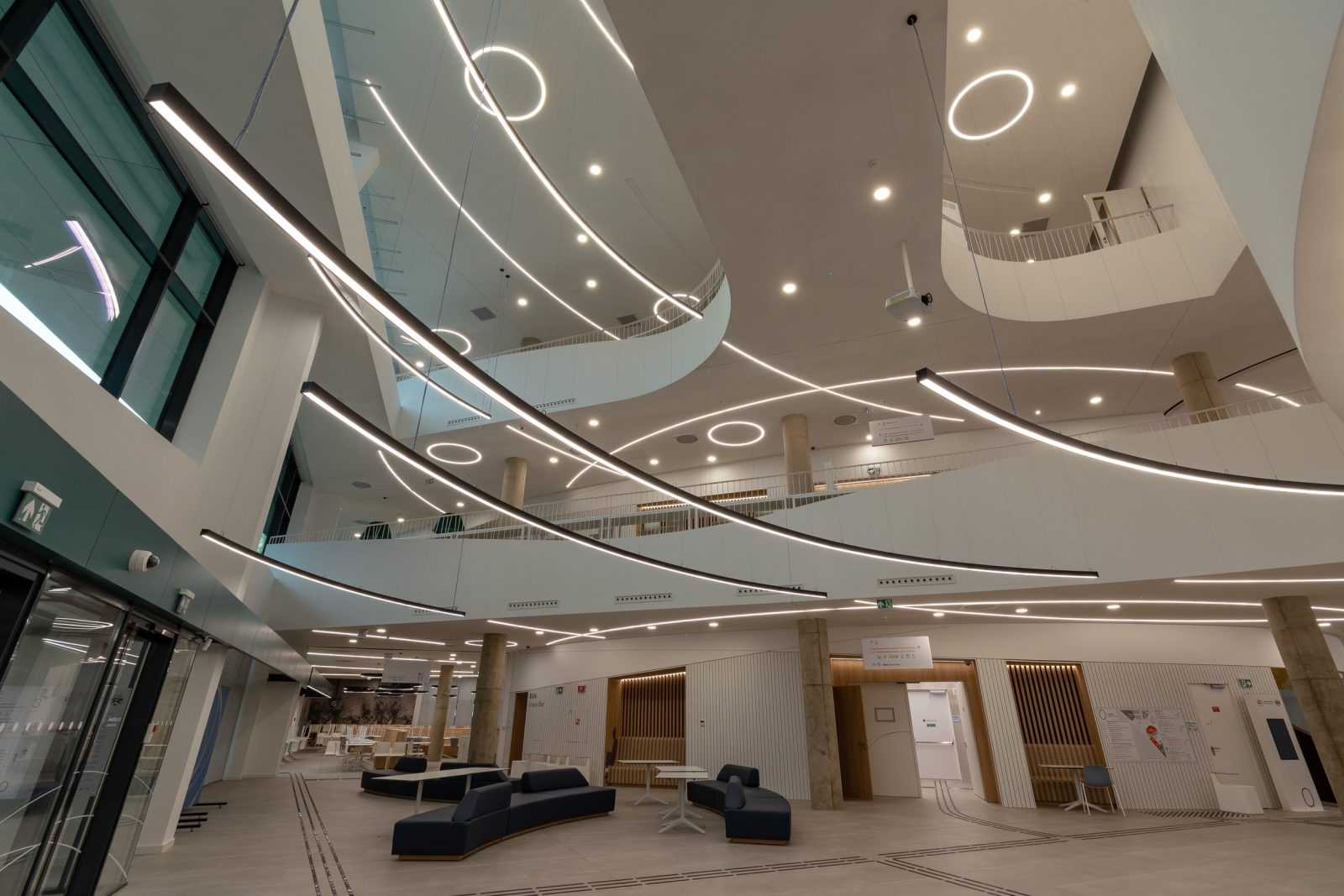 Modern multi-level interior with curved lighting and seating areas.