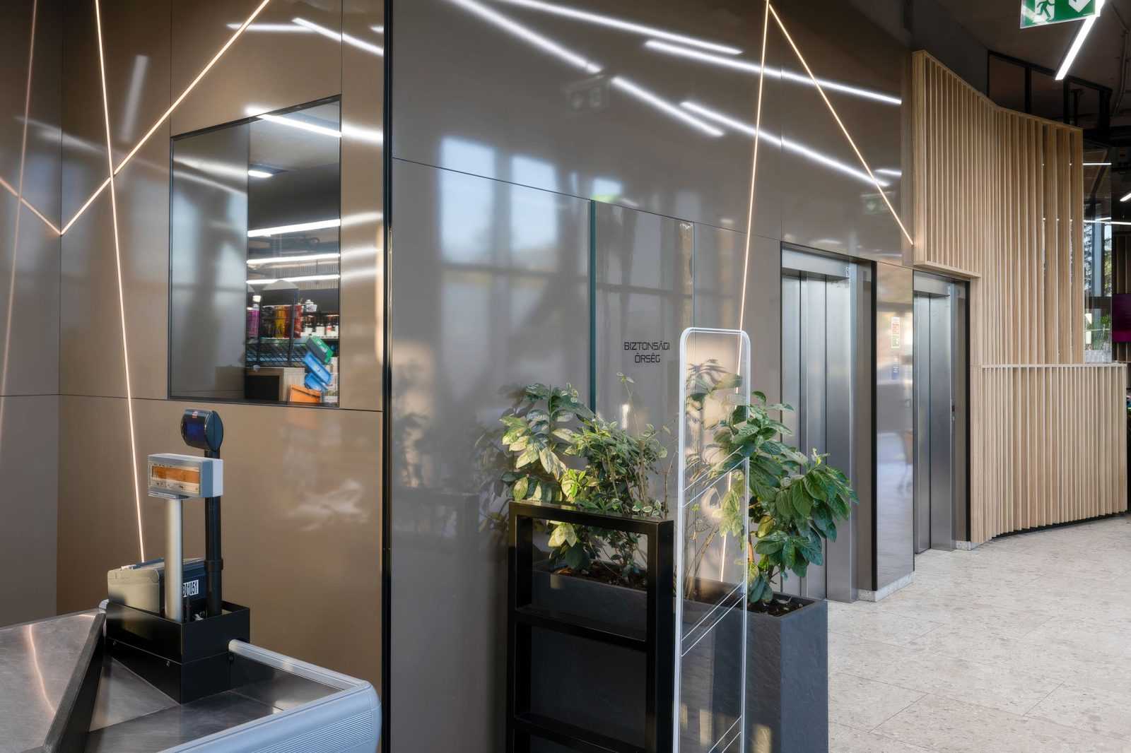 Modern lobby with glass walls, elevators, and indoor plants at Megaholz.