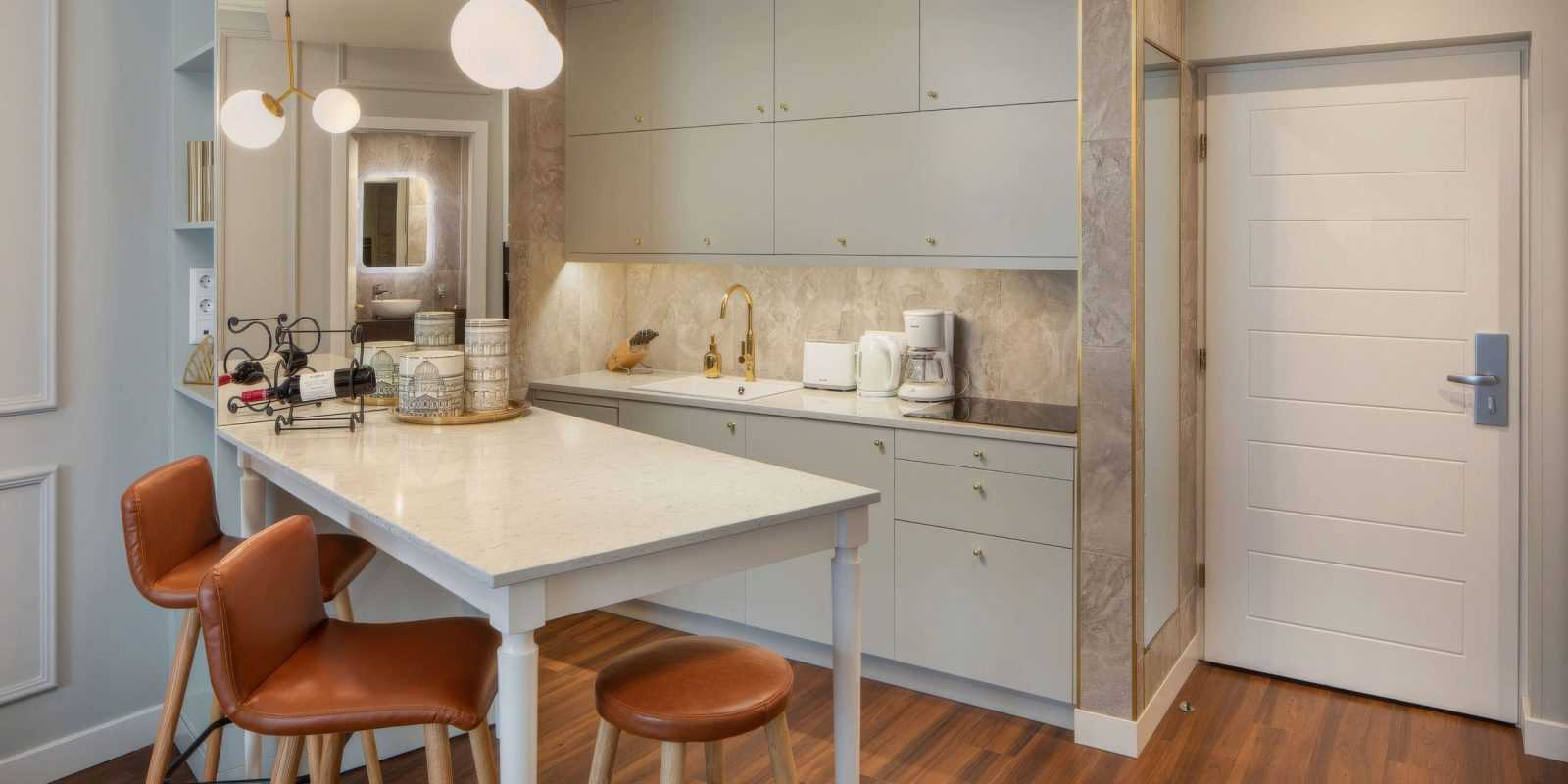 Modern kitchen with marble countertop and leather bar stools.