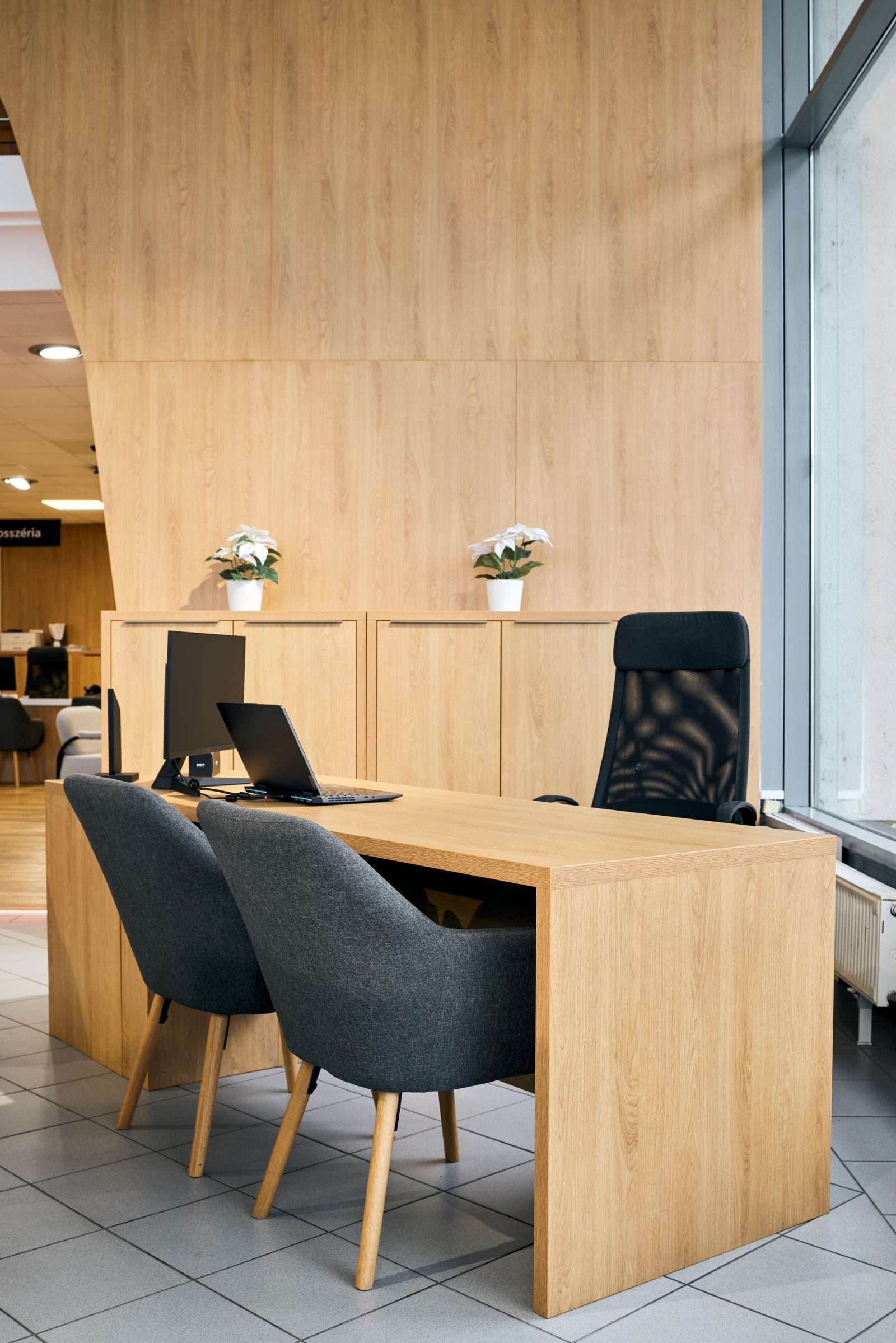 Modern wooden office desk with chairs and laptop.