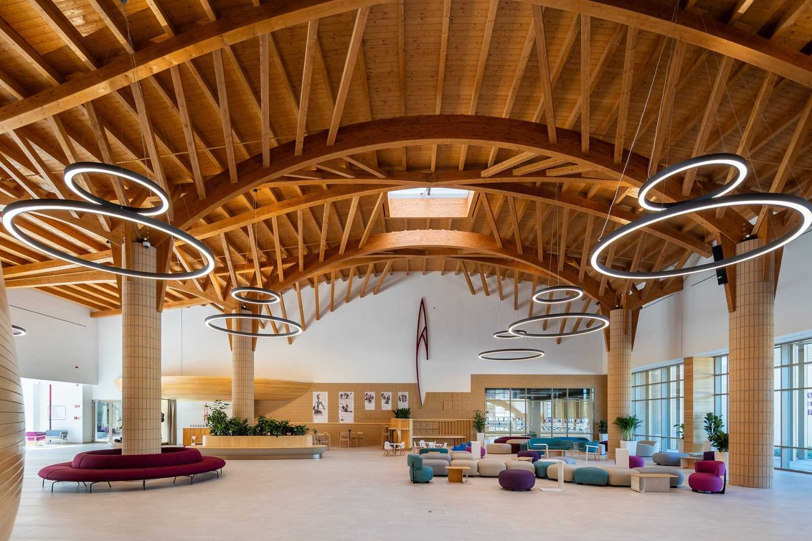 Modern wooden ceiling with circular lights in a spacious lobby.