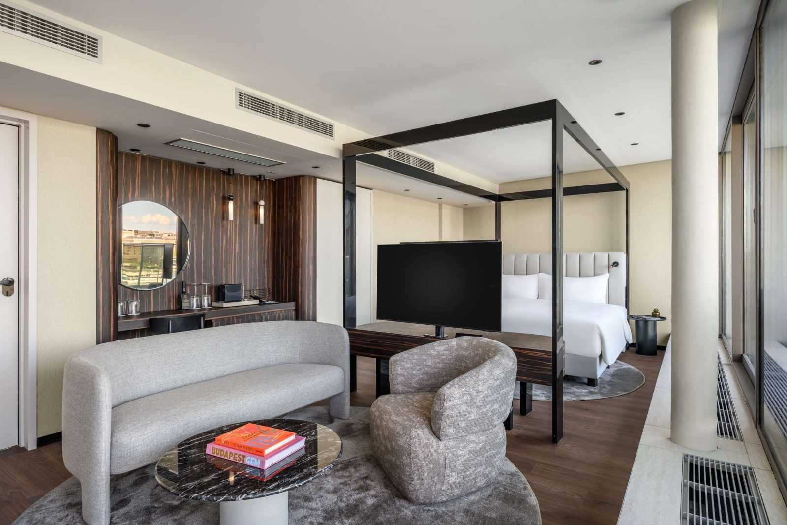 Modern hotel room with sleek furniture and large bed.