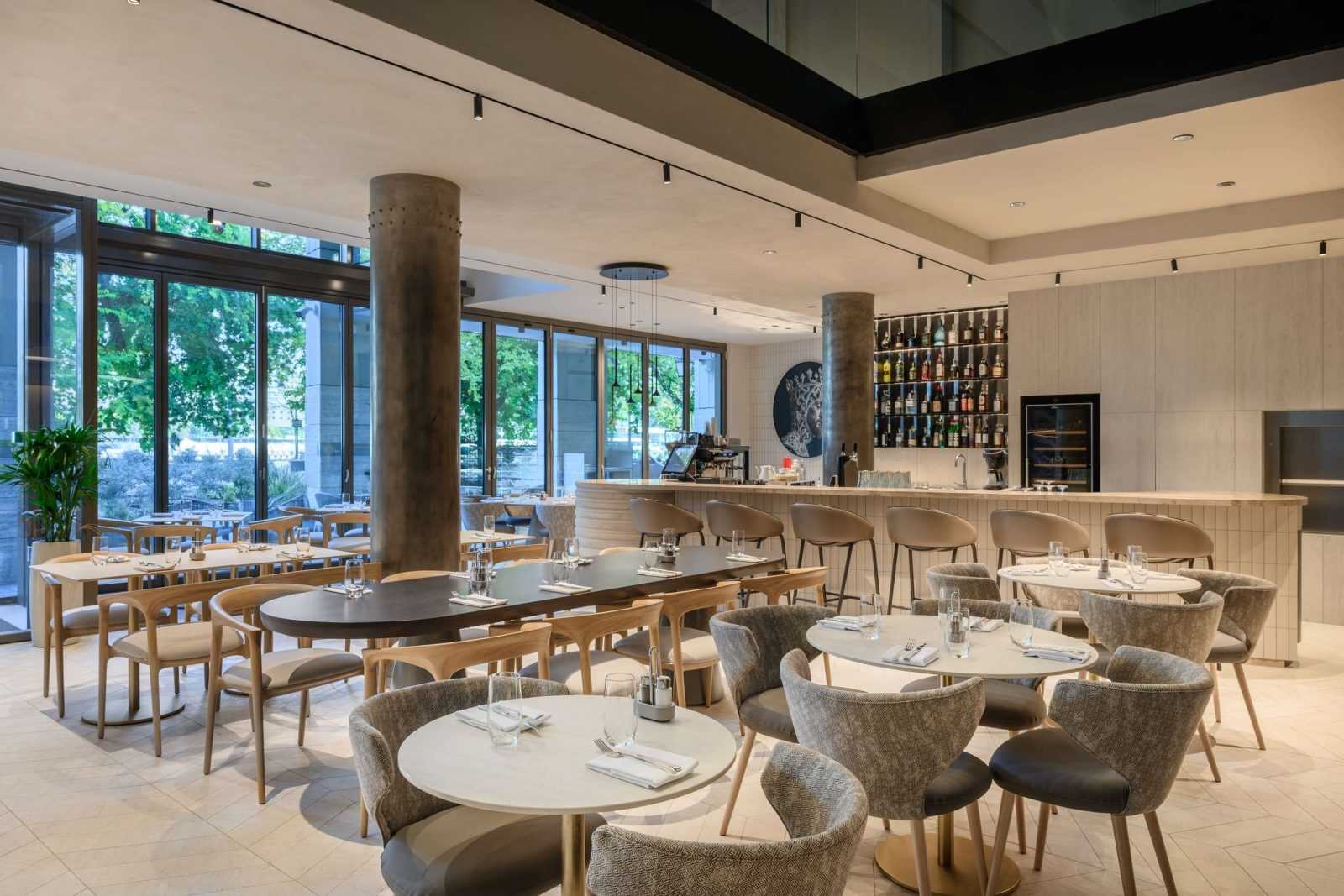 Modern restaurant interior with wooden tables, chairs, and large windows at Megaholz.