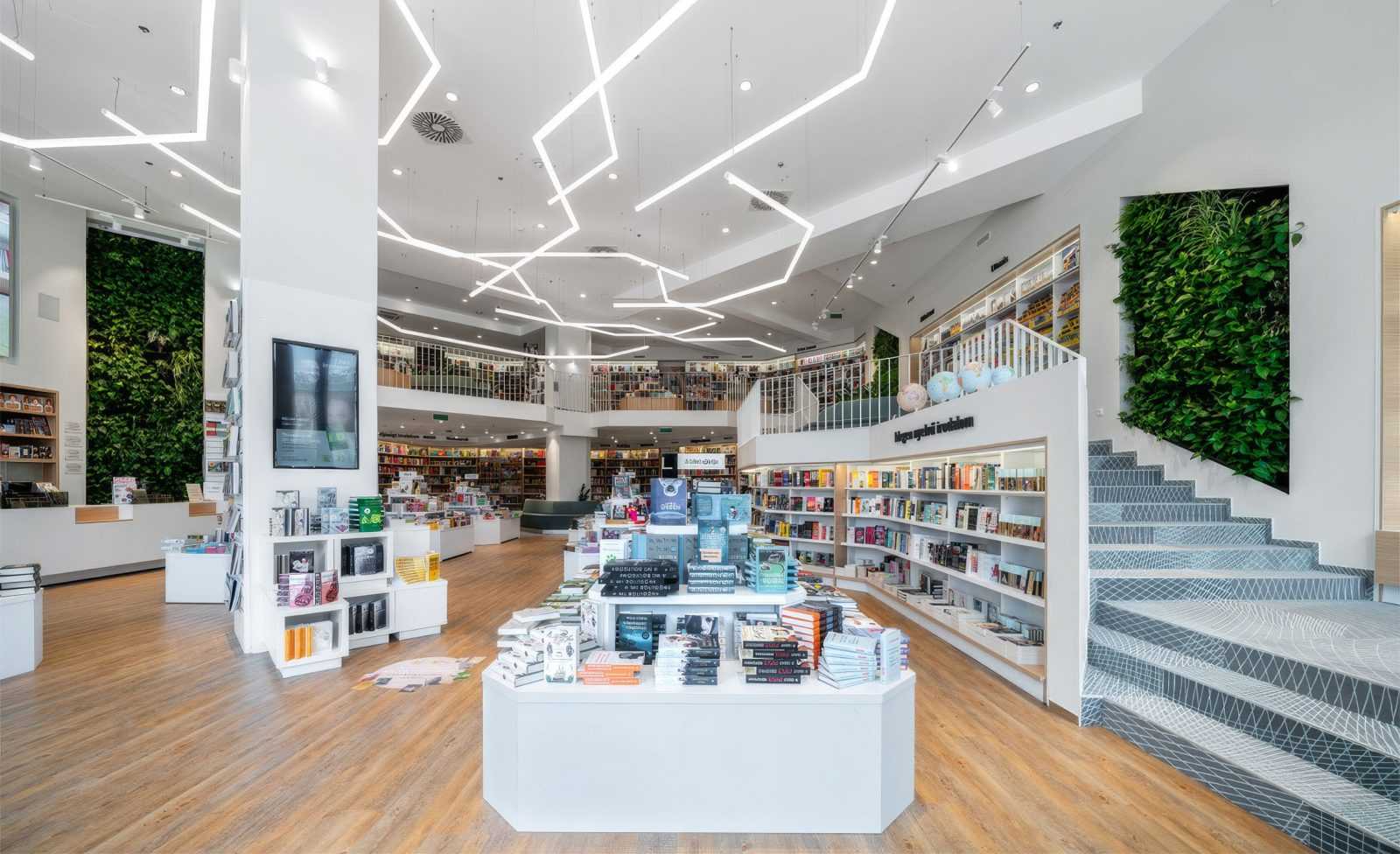 Modern bookstore interior with bookshelves, green walls, and geometric lighting.