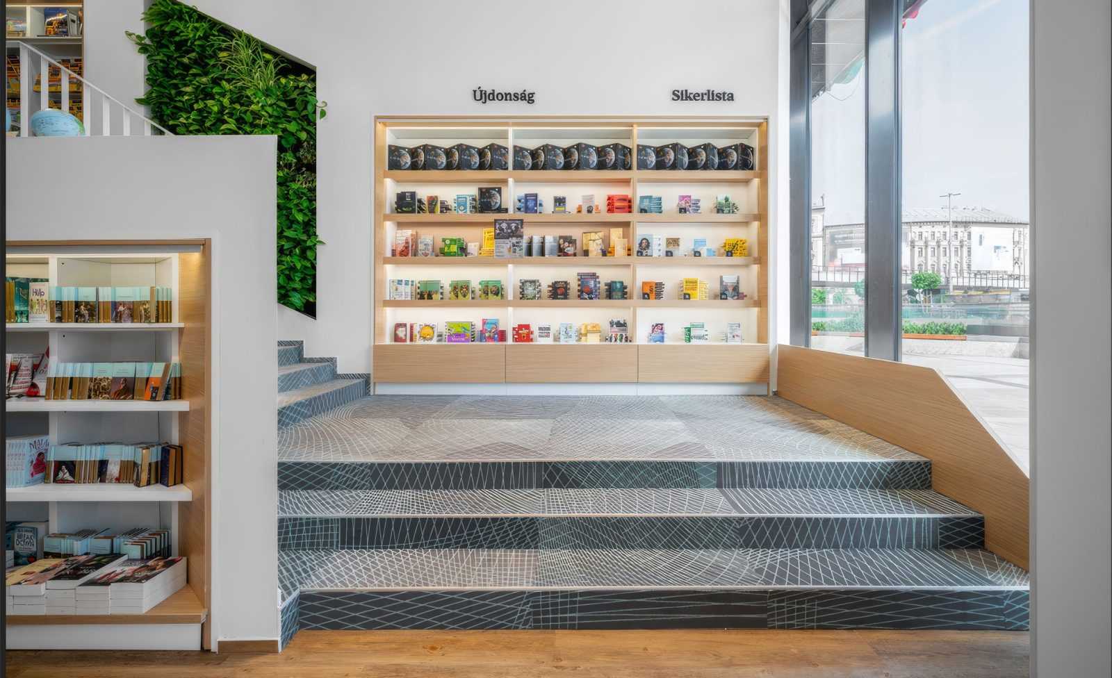 Modern bookstore interior with wooden shelves, green wall, and patterned stairs.