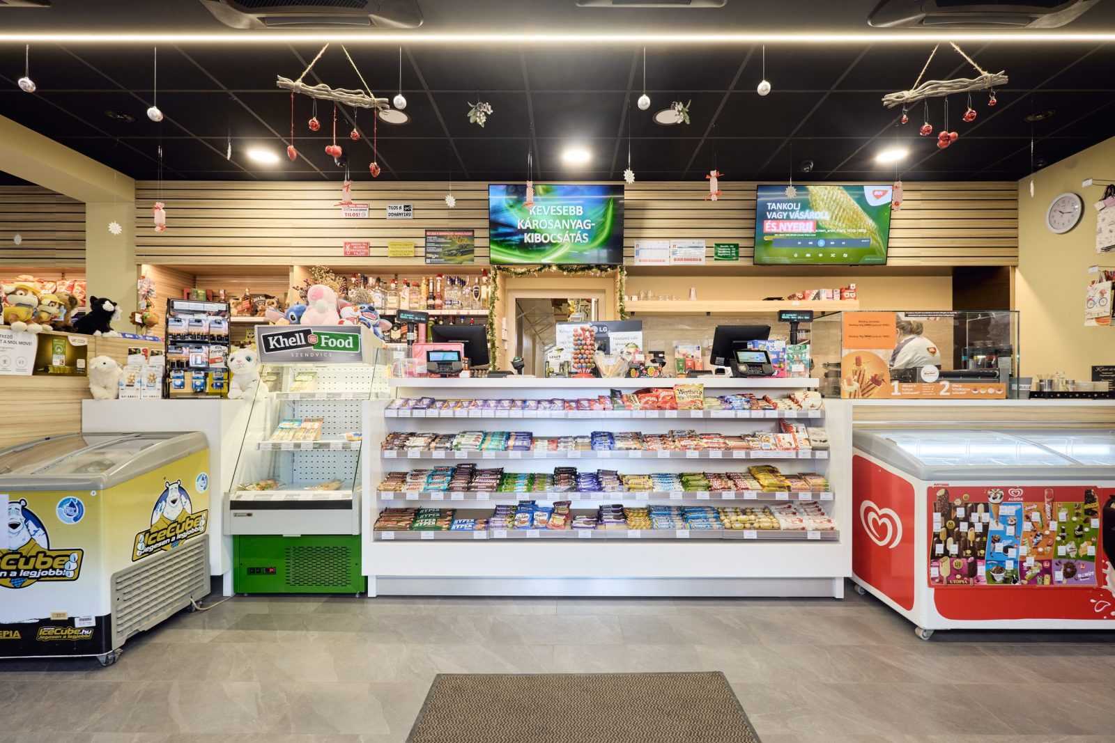 Modern gas station convenience store interior with snacks and ice cream freezers.