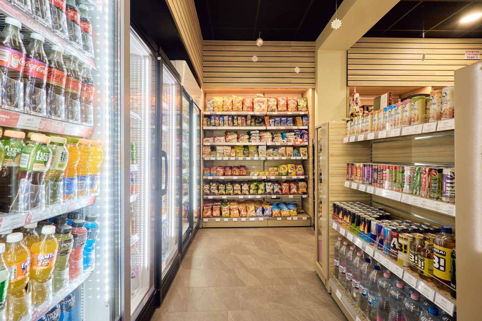 Modern convenience store aisle with refrigerated drinks and snack shelves.