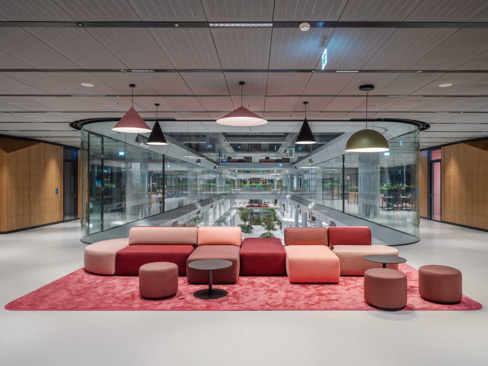 Modern office lounge with red sofas and glass atrium.