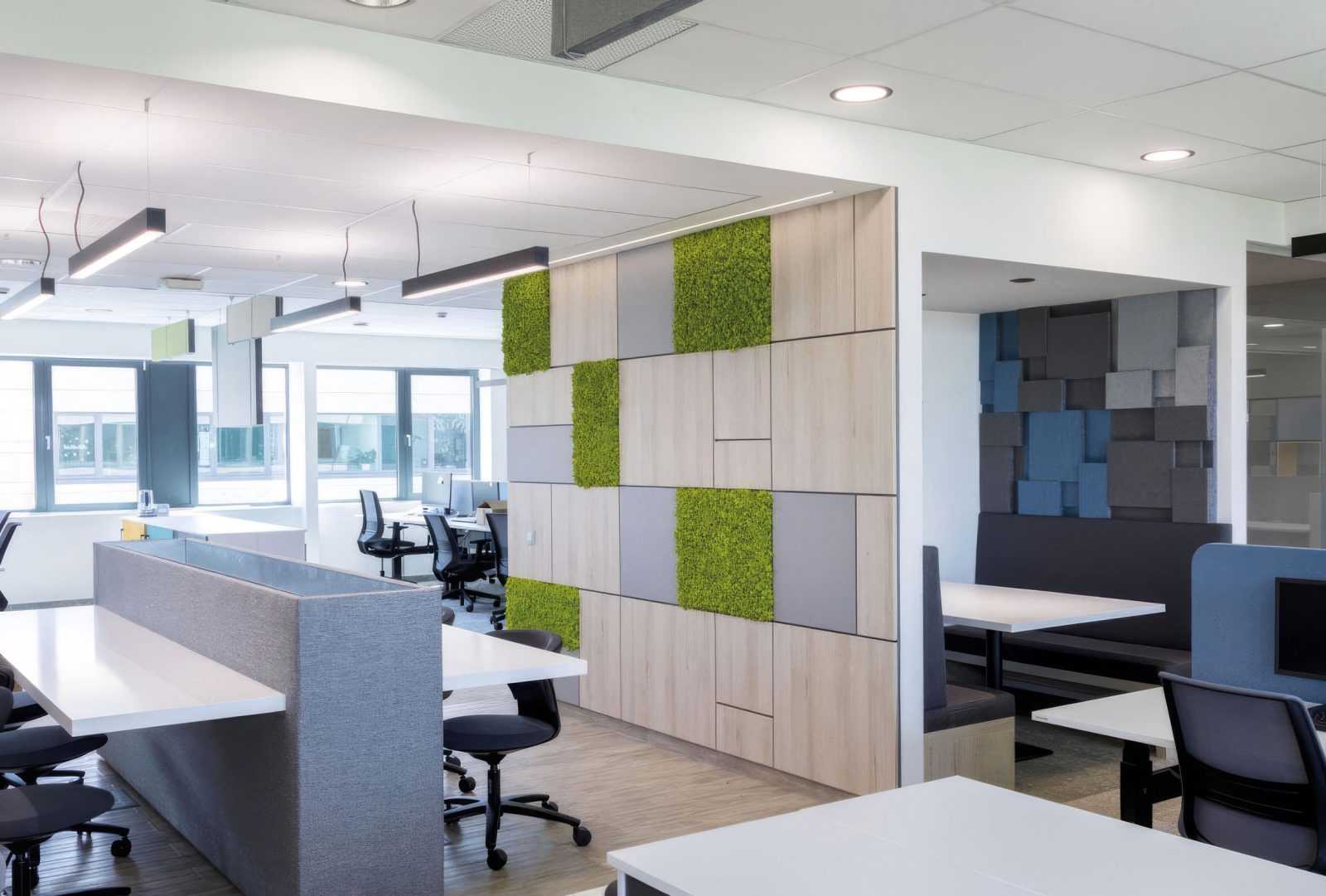 Modern office interior with green wall panels and ergonomic workstations.