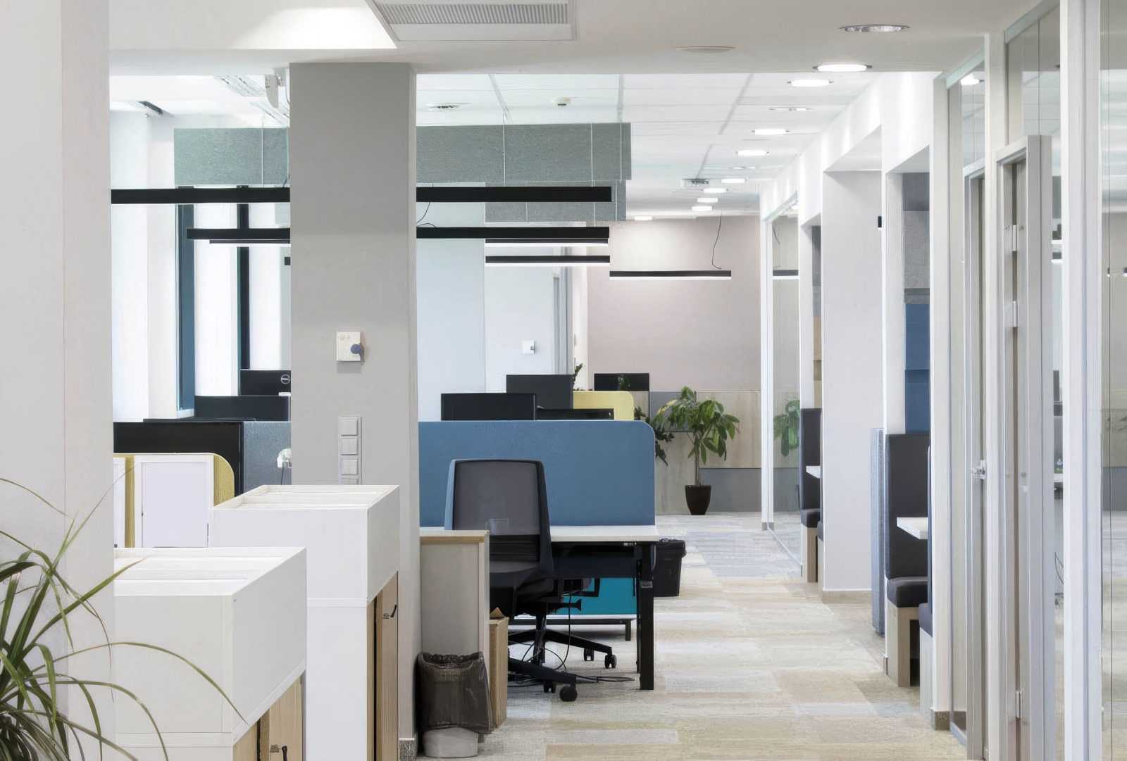 Modern office interior with workstations and glass partitions.