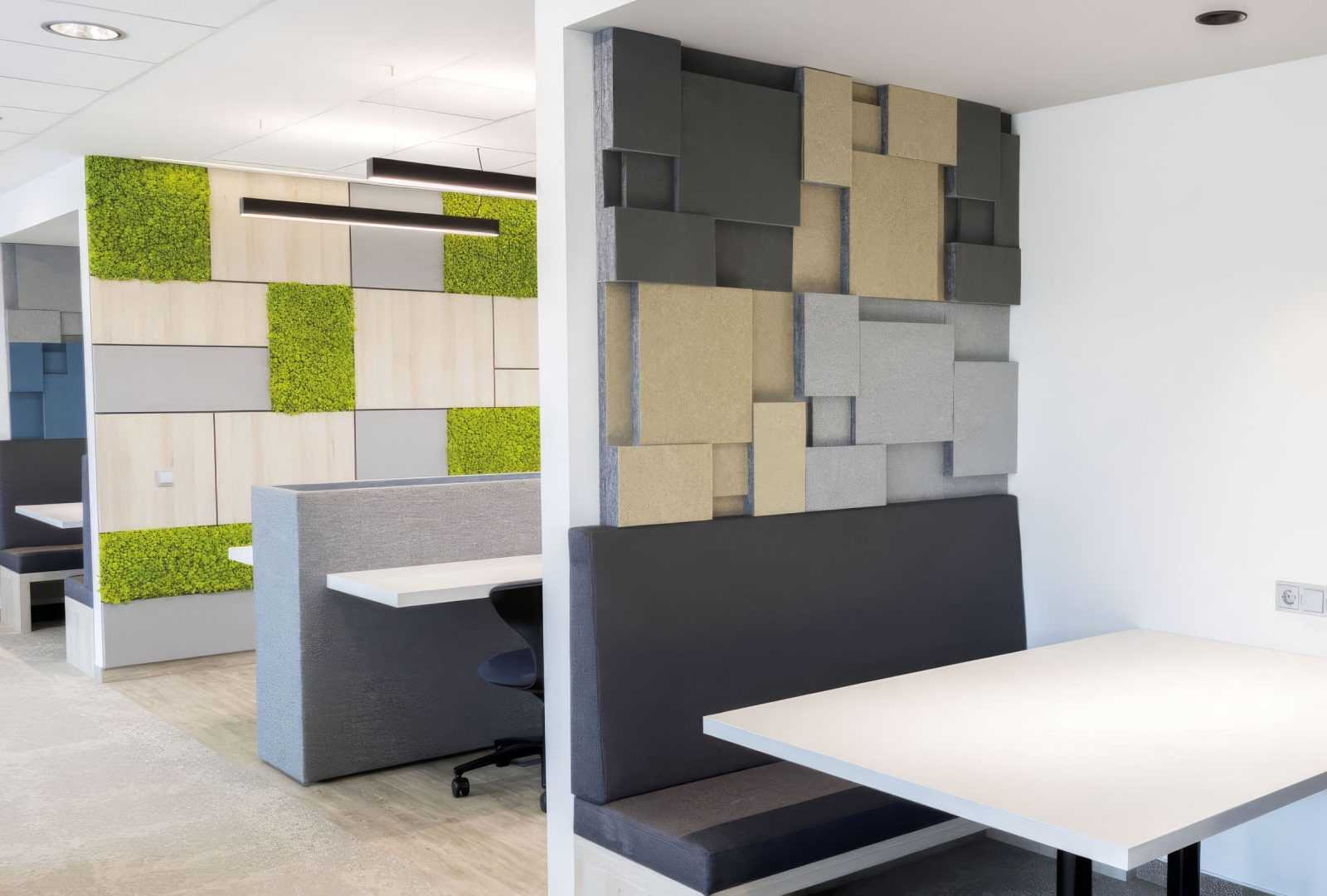 Modern office interior with green moss walls and geometric acoustic panels.