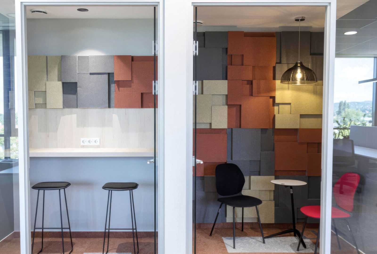 Modern office meeting rooms with colorful geometric wall panels and glass partitions.