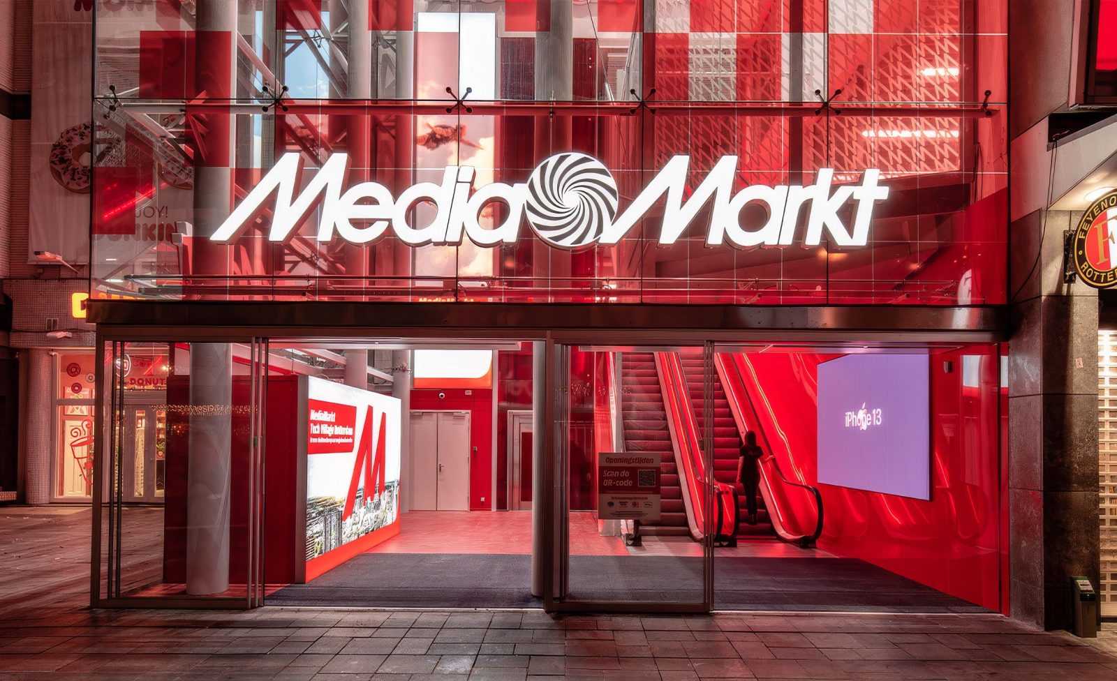 MediaMarkt store entrance with red glass facade and iPhone 13 advertisement.