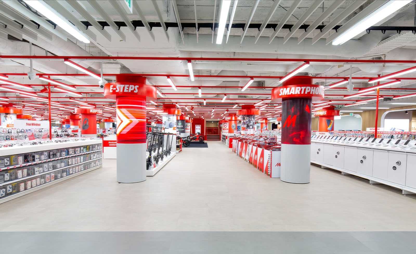 Megaholz store interior with red and white columns, showcasing smartphone and e-steps sections.