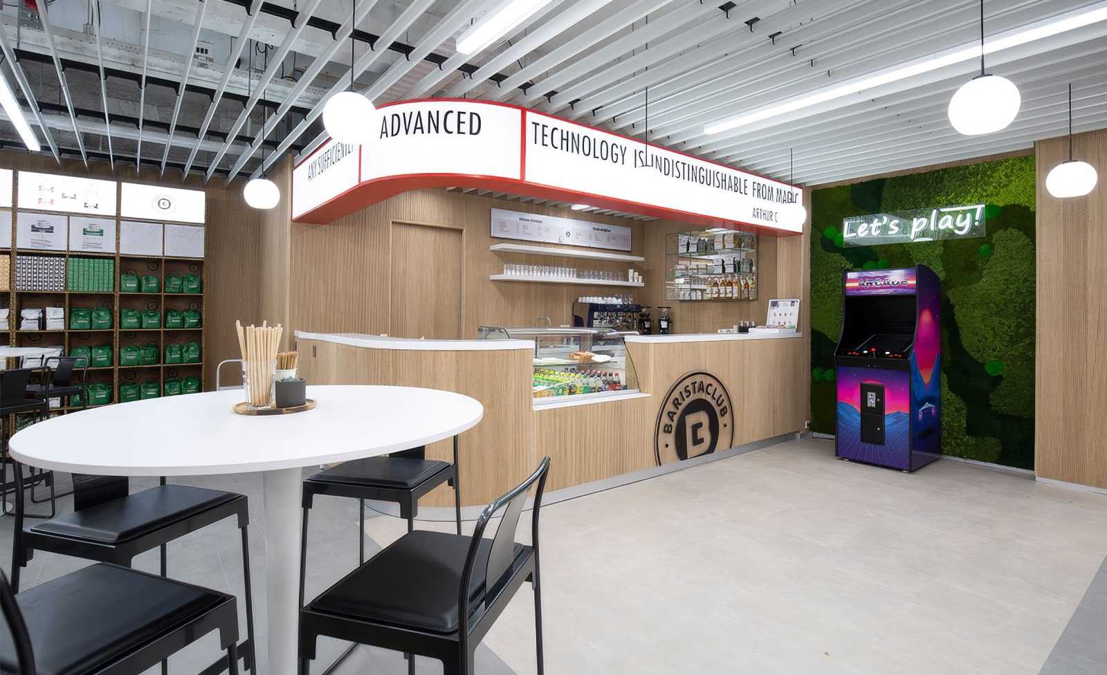 Modern coffee shop interior with arcade machine and wooden counter.
