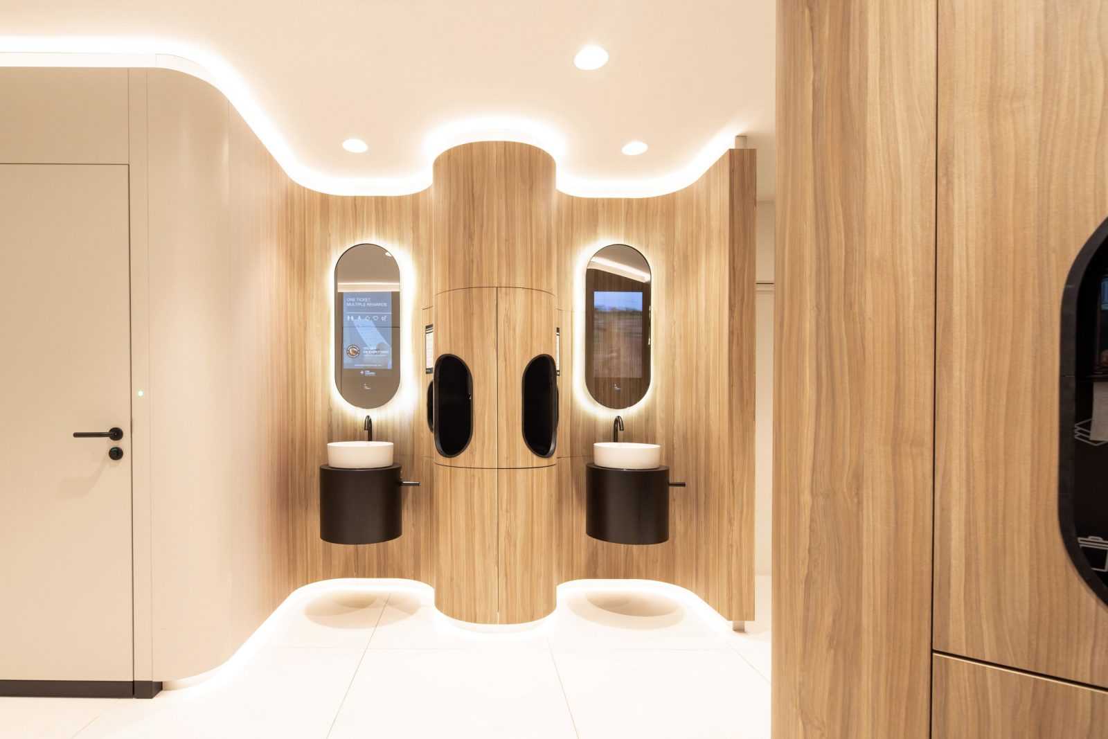 Modern wooden restroom with sleek sinks and smart mirrors.
