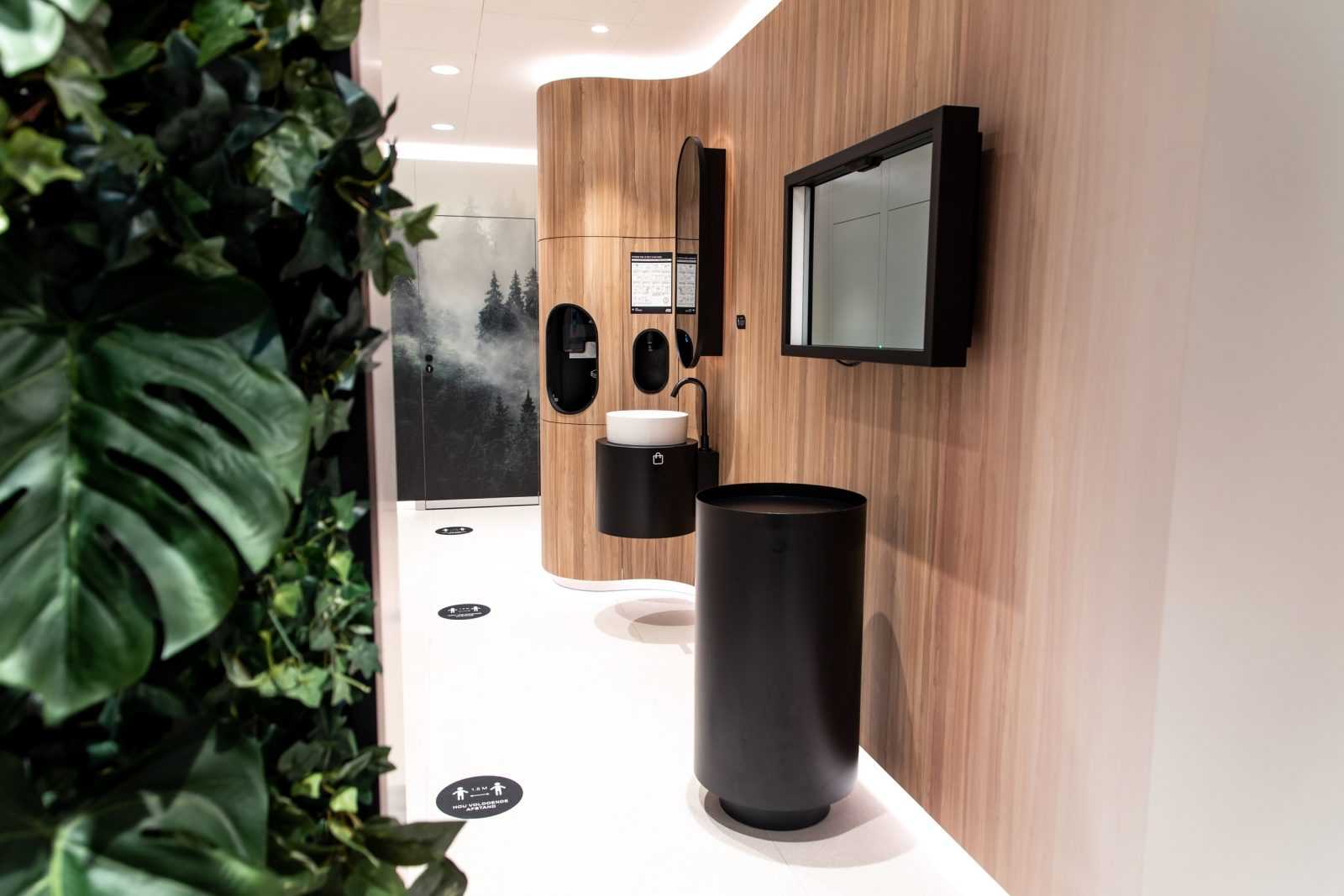 Modern wooden bathroom with black fixtures and greenery.