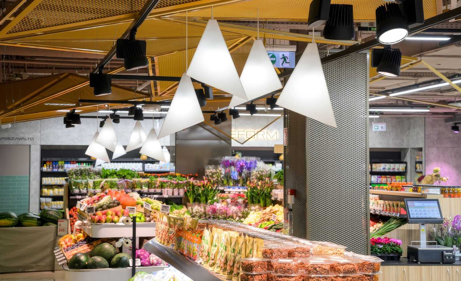 Modern supermarket interior with fresh produce and hanging lights.