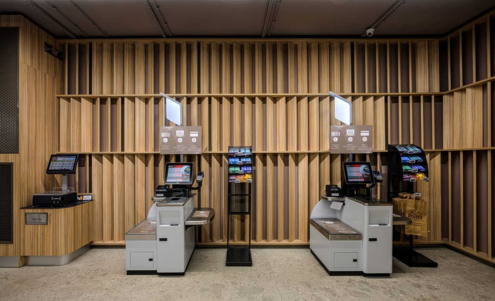 Modern self-checkout kiosks in a wooden interior store.